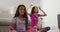 Hispanic mother and daughter sitting on the floor meditating at home