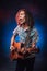 Hispanic musician emotionally singing and playing guitar on a dark illuminated by blue and red light