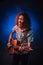 Hispanic musician emotionally singing and playing guitar on a dark illuminated by blue and red light