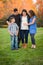 Hispanic Pregnant Family Portrait Against Fall Colored Trees