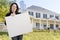 Hispanic Realtor Holding Blank Sign In Front of House