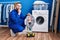 Hispanic repairman working on washing machine serious face thinking about question with hand on chin, thoughtful about confusing