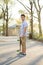 Hispanic skateboarder stands in the park looking far out over th