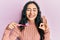 Hispanic teenager girl with dental braces holding mouthwash and toothbrush for fresh breath doing ok sign with fingers, smiling