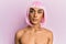 Hispanic transgender man wearing make up and pink wig with serious expression on face