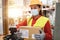 Hispanic warehouse worker woman holding delivery box while wearing safety mask - Focus on face