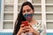 Hispanic Woman covering her face with protective mask and using smartphone