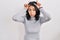 Hispanic woman with dark hair standing over isolated background doing funny gesture with finger over head as bull horns