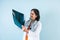 Hispanic woman doctor looks at xray radiography images in radiology clinic on blue background in Mexico Latin America