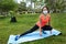Hispanic Woman facing the camera while is doing yoga with a mattress in a park wearing a mask