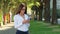 Hispanic woman with glasses typing message in social media on the street