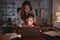 Hispanic woman looking over her sonï¿½s shoulder while he does his homework using laptop computer