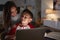 Hispanic woman looking over her sonï¿½s shoulder while he does his homework using laptop computer