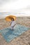 Hispanic woman with parasol on beach blanket