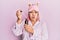 Hispanic woman with pink hair wearing pajama using night serum puffing cheeks with funny face