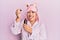 Hispanic woman with pink hair wearing pajama using night serum winking looking at the camera with sexy expression, cheerful and