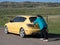Hispanic Woman Pushing a Compact Yellow Car