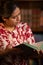 Hispanic Woman Reading Book with Bookshelf in Background