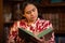 Hispanic Woman Reading Book with Bookshelf in Background