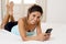 Hispanic woman relaxed using internet mobile phone sending message at home bedroom smiling happy