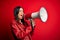 Hispanic woman shouting angry on protest through megaphone