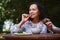 Hispanic woman sits at rustic wooden dining table, tasting traditional Ukrainian borscht with sliced bacon and rye bread