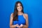 Hispanic woman standing over blue background smiling with hands palms together receiving or giving gesture