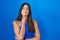 Hispanic woman standing over blue background touching painful neck, sore throat for flu, clod and infection