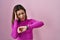 Hispanic woman standing over pink background looking at the watch time worried, afraid of getting late