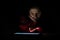 Hispanic Woman Using Electronic Tablet in Dark Environment Lit by Tablet