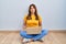 Hispanic woman using laptop sitting on the floor at home making fish face with lips, crazy and comical gesture