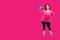 Hispanic Woman In Workout Clothes Holding Dumbbell Against A Bright Magenta Pink Background
