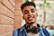 Hispanic young man smiling wearing headphones leaning on bricks wall