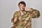 Hispanic young man wearing camouflage army uniform pointing with hand finger to face and nose, smiling cheerful