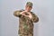Hispanic young man wearing camouflage army uniform smiling in love doing heart symbol shape with hands