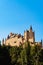 Historic Alcazar Castle surrounded by green trees in Segovia, Spain