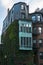 Historic brownstone houses with big windows and copper teal wall in Boston, Massachusetts. Climbing ivy plant on the wall