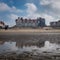 Historic building in De Haan, reflected in a water puddle on the beach