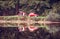 Historic car with mini caravan is reflected in lake, red filter