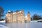 Historic castle in winter landscape with snow and frozen moat. Sunny day with bright blue sky, low angle perspective. Old medieval