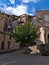 Historic center of Sisteron in Provence, France with square surrounded by old buildings and a single tree with green leaves.