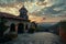 A historic chapel basks in the twilight glow, overlooking a peaceful mountainous horizon under a dramatic sky