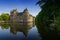 The historic Chateau Trecesson castle reflected in the pond in cool dark blue evening light