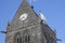 Historic church of Sainte mere l`eglise, with a paratrooper hanging on the bell tower.