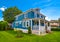 Historic family house with green lawn in front and blue sky background.