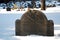 A historic gravestone is partially buried in the snow
