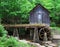 A historic mill in a forest with green leafs in late spring.