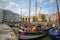 Historic sailing vessels moored along pier in city`s Old Harbour area with apartment buildings in background