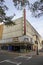 The Historic Savannah Theatre with a tall red neon sign, colorful chairs and bicycles with lush green trees and blue sky