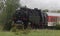 Historic steam locomotive with passenger wagons on rail tracks